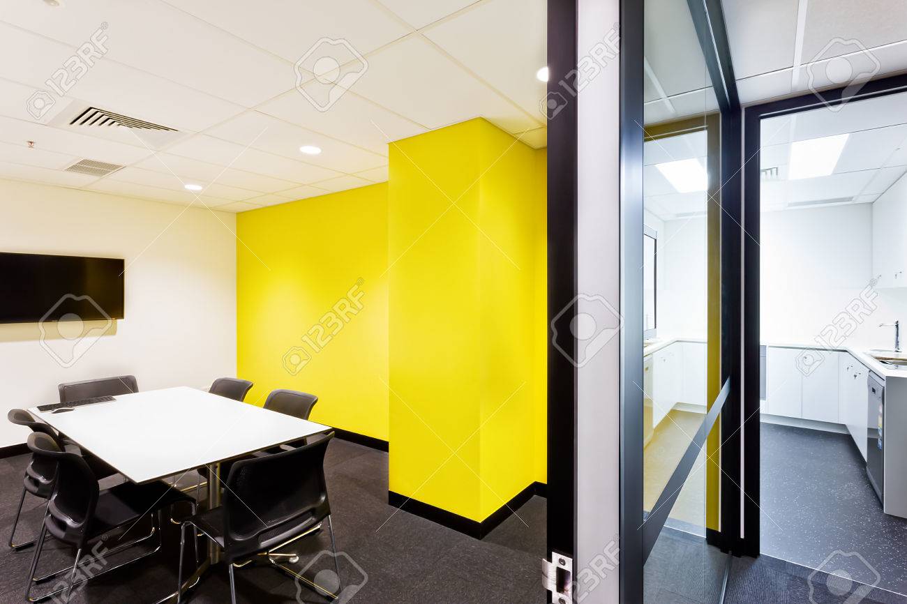 small conference room with yellow walls and hallway to the kitchen