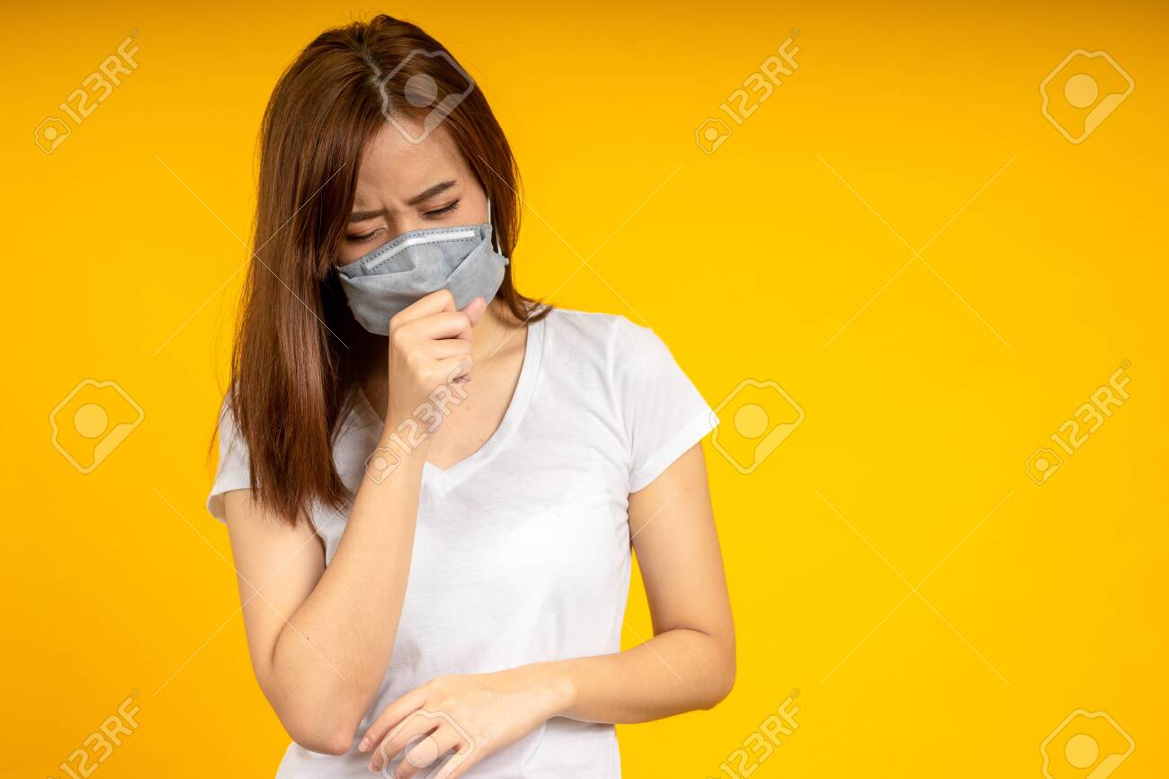 Asian woman is coughing or sneezing wearing hygienic mask to protect virus, COVID 19 or Colona Virus infection and dust PM 2.5 pollution isolate on yellow background - 144033984 Asian woman is coughing or sneezing wearing hygienic mask to protect virus, COVID 19 or Colona Virus infection and dust PM 2.5 pollution isolate on yellow background - 144033984