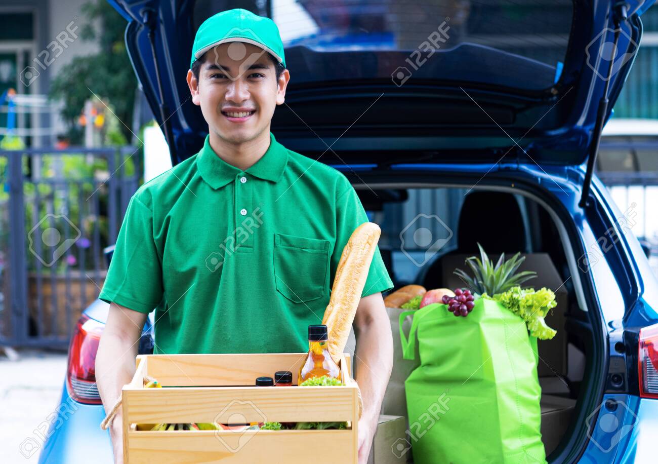 Asian delivery man in green t-shirt delivering food, fruit, joice and vegetable to home - online grocery shopping service concept - 148856528 Asian delivery man in green t-shirt delivering food, fruit, joice and vegetable to home - online grocery shopping service concept - 148856528