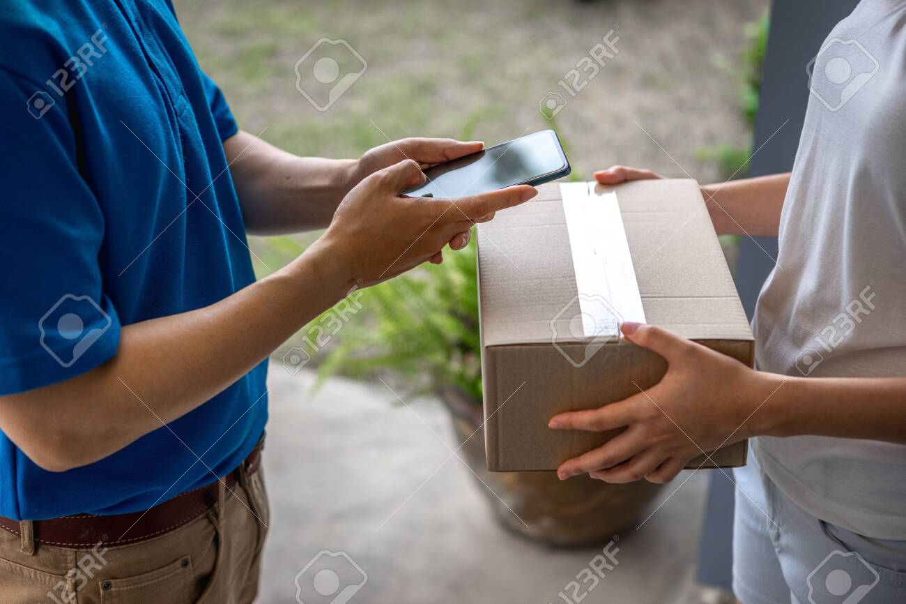 Asian deliveryman is delivering parcel to house her to sign to receive the product After she ordered online during the outbreak of the coronavirus or Covid-19 virus. - 148855844 Asian deliveryman is delivering parcel to house her to sign to receive the product After she ordered online during the outbreak of the coronavirus or Covid-19 virus. - 148855844