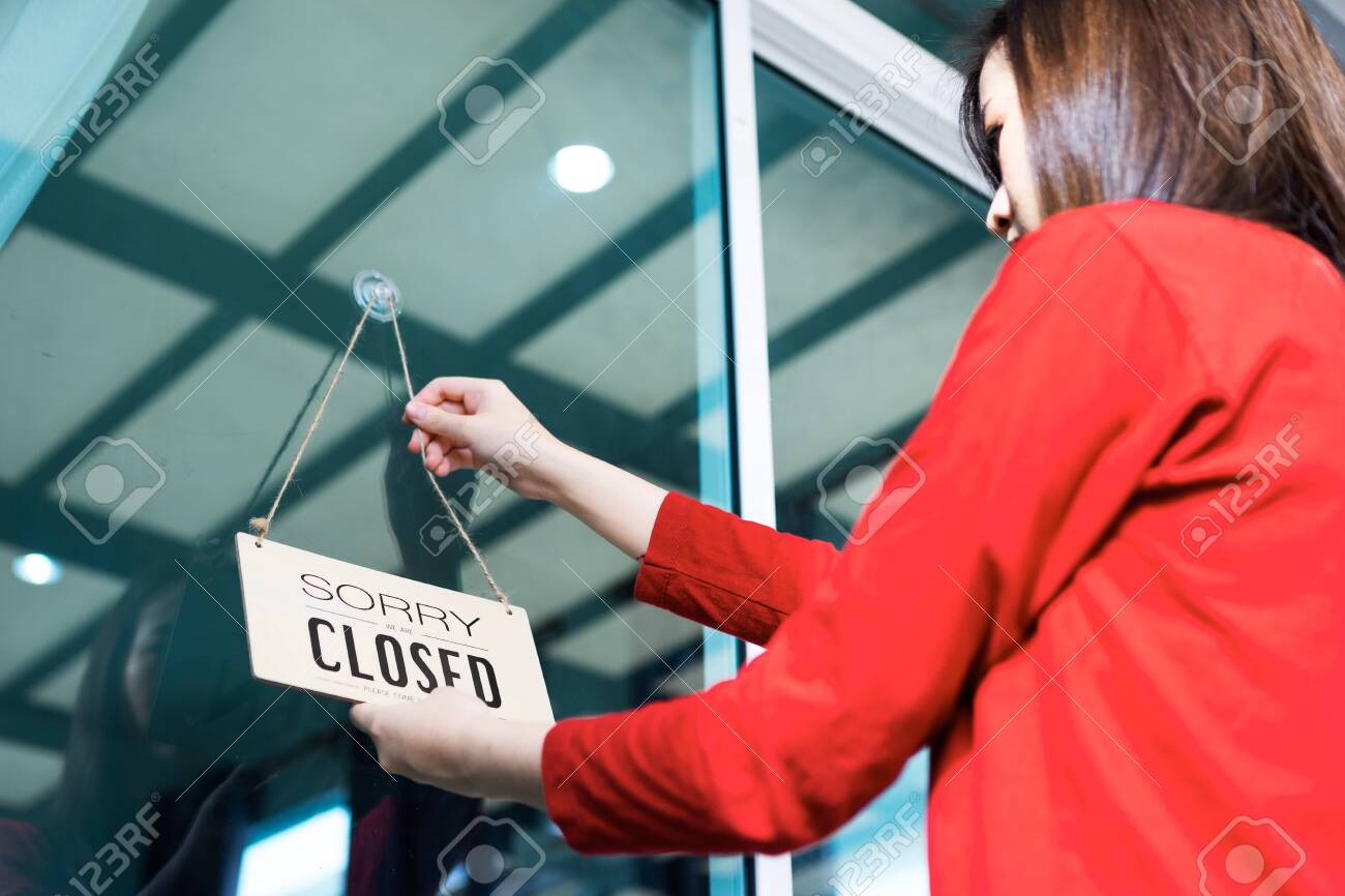 Asian woman shop owner hanging label 'Sorry we are Closed'. She close her shop under pandemic coronavirus - 149473795 Asian woman shop owner hanging label 'Sorry we are Closed'. She close her shop under pandemic coronavirus - 149473795