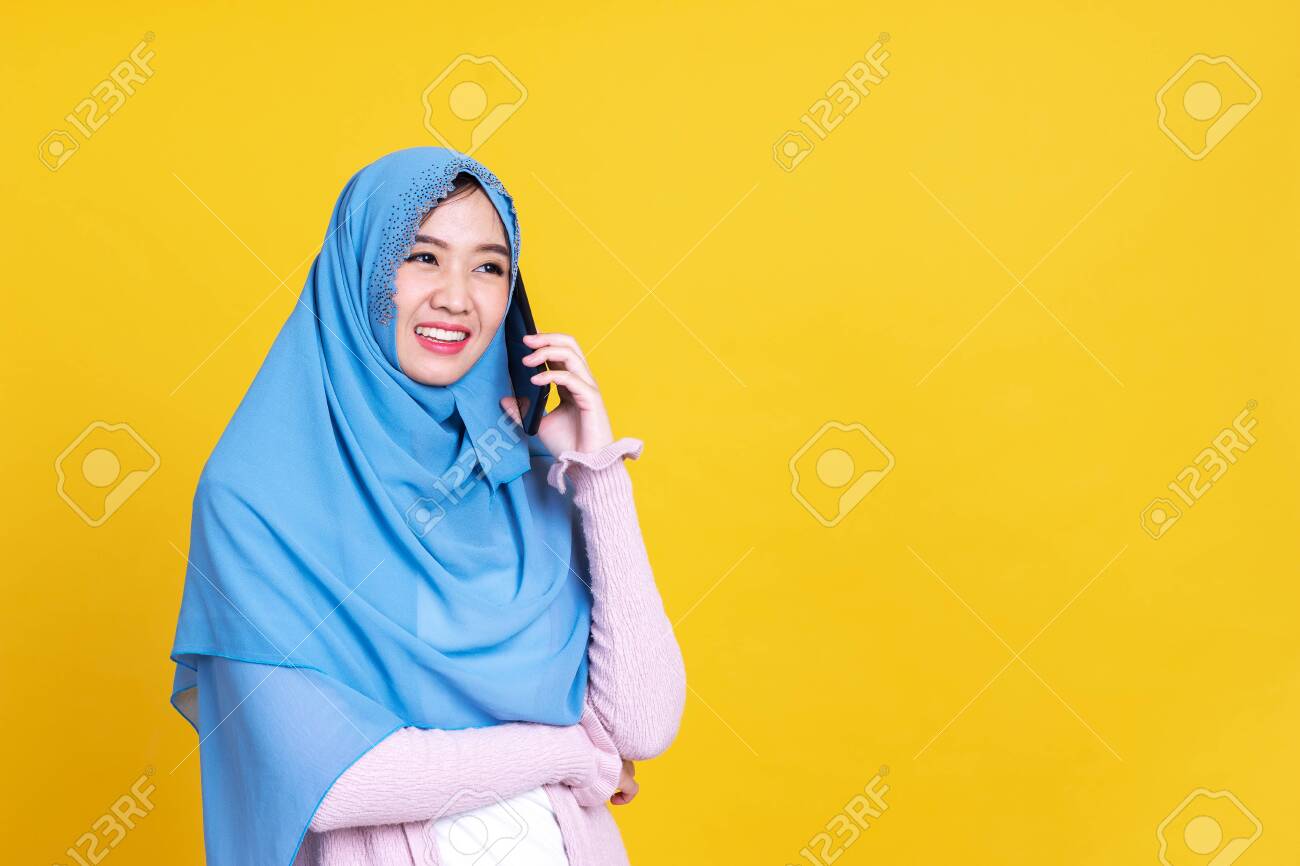Smiling Asian muslim woman with using mobile or smartphone over isolated color background. - 149473867 Smiling Asian muslim woman with using mobile or smartphone over isolated color background. - 149473867