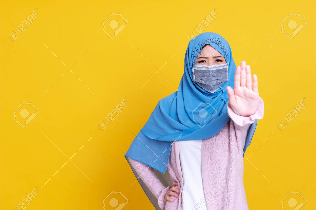 Asian serious muslim woman wears hijab, makes cross with hands over chest, shows stop or prohibition gesture, disagrees with uninteresting offer, isolated over blue background. No sign - 149473939 Asian serious muslim woman wears hijab, makes cross with hands over chest, shows stop or prohibition gesture, disagrees with uninteresting offer, isolated over blue background. No sign - 149473939