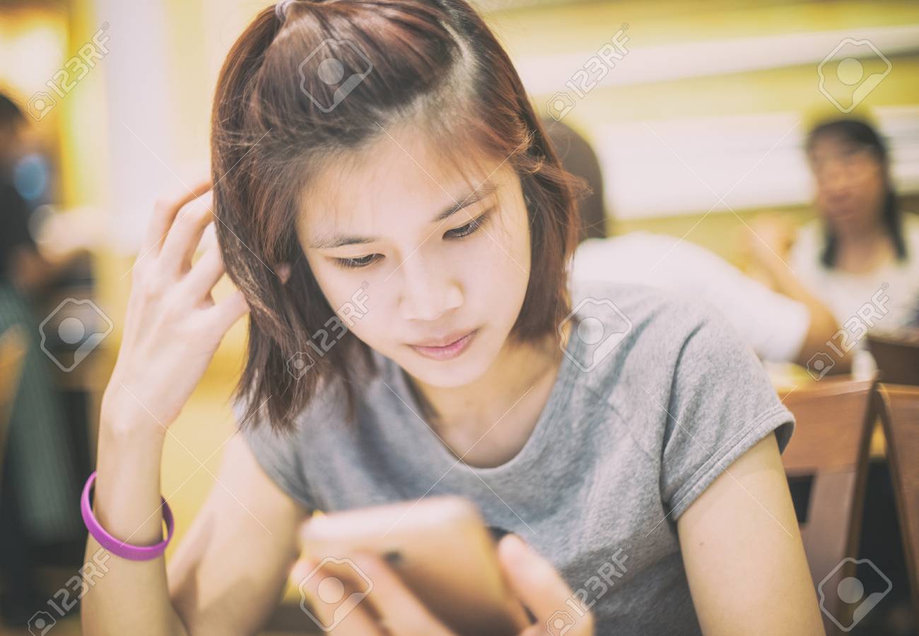 Cute Short Hair Asian Girl Using A Mobile Phone In Cafe