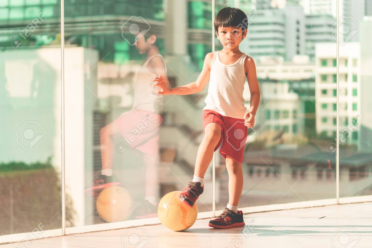 O Menino Do Jogador De Futebol Está Pisando Na Bola Na Sala Foto