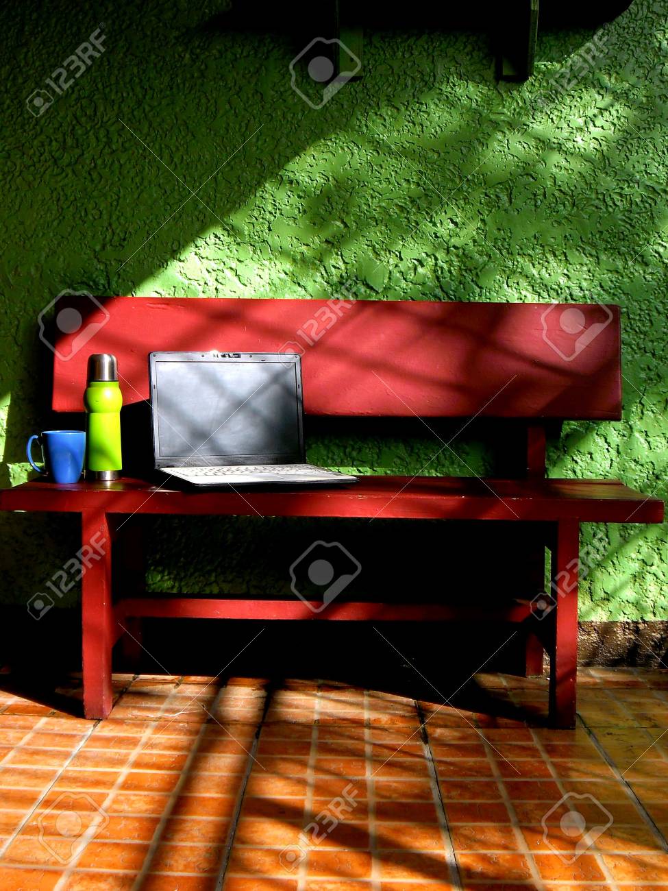 coffee mug flask laptop computer and red wooden bench in a