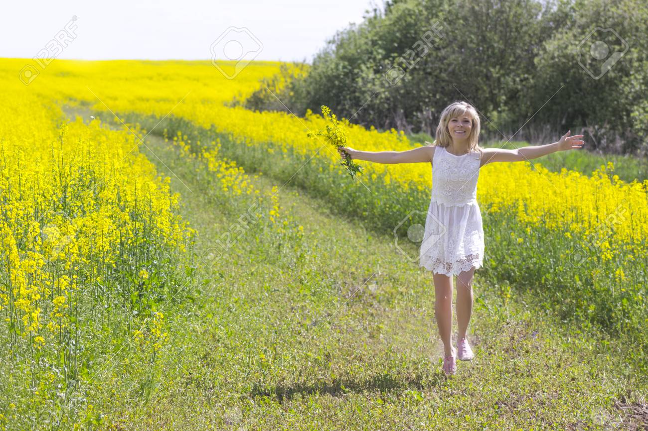 国の道路の上を歩いての菜の花の花束を持つ少女 の写真素材 画像素材 Image