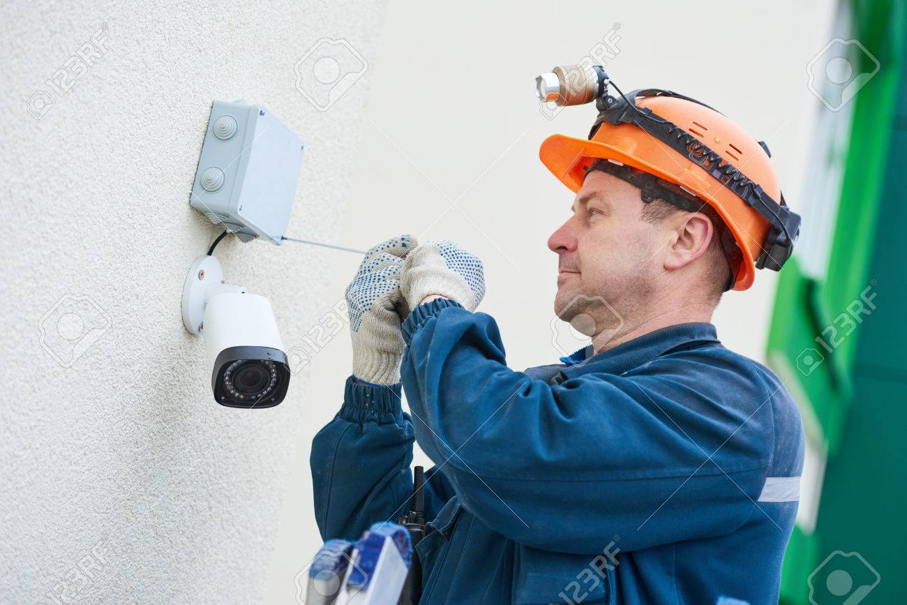 video surveillance technician worker installing wall camera construction surveillance technician