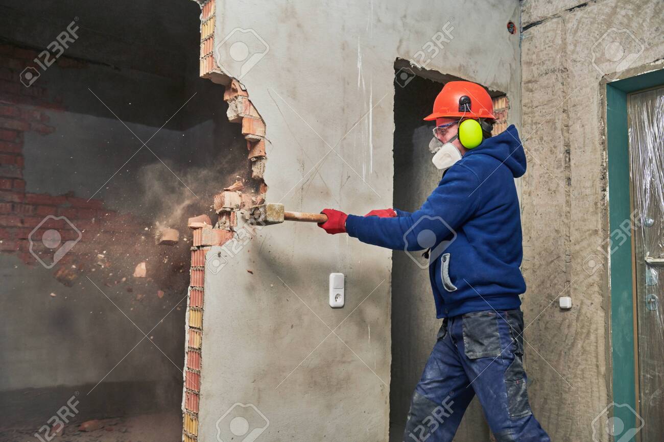 demolition work and rearrangement. worker with sledgehammer destroying wall - 118735881 demolition work and rearrangement. worker with sledgehammer destroying wall - 118735881
