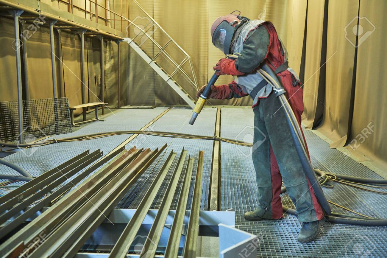 Sandblasting in chamber. Worker makes sand blast cleaning of metal detail - 132919585 Sandblasting in chamber. Worker makes sand blast cleaning of metal detail - 132919585