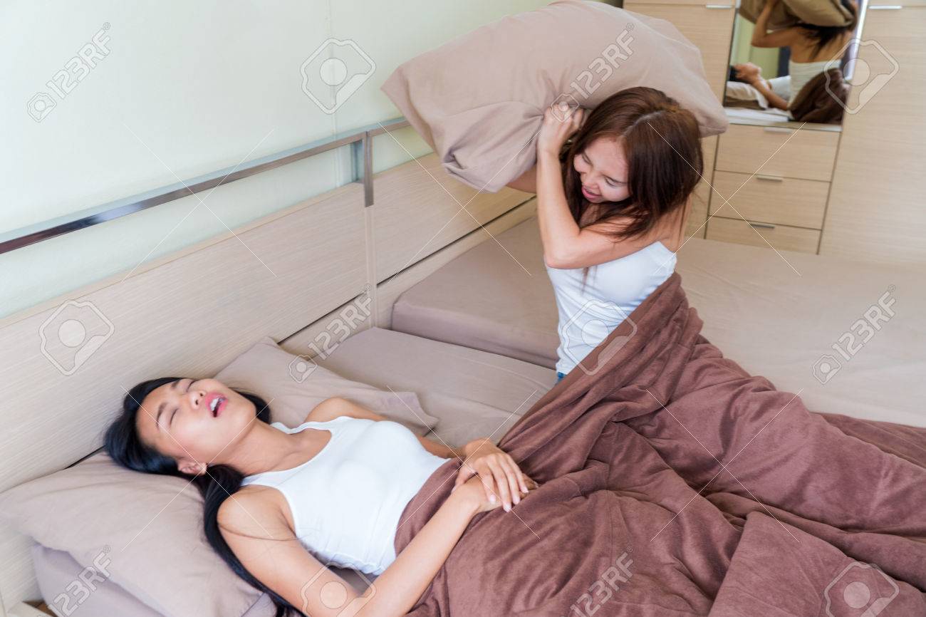 ベッドと枕を保持彼女のルームメイトでいびきをかく女性 の写真素材 画像素材 Image