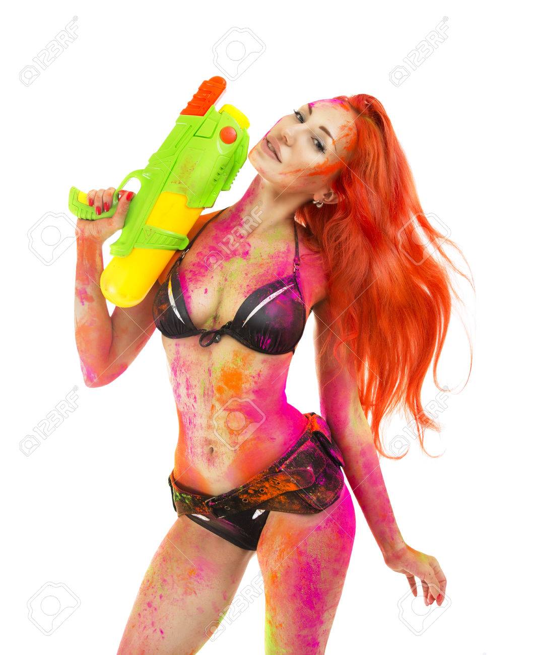 Happy Holi Festival! Holi Celebration Party - Beautiful Sexy Girl In Bikini  With Toy Gun Colored Dry Bright Multicolor Paint Powder On White  Background. Indian Traditional Spring Festival In Goa Фотография, картинки,