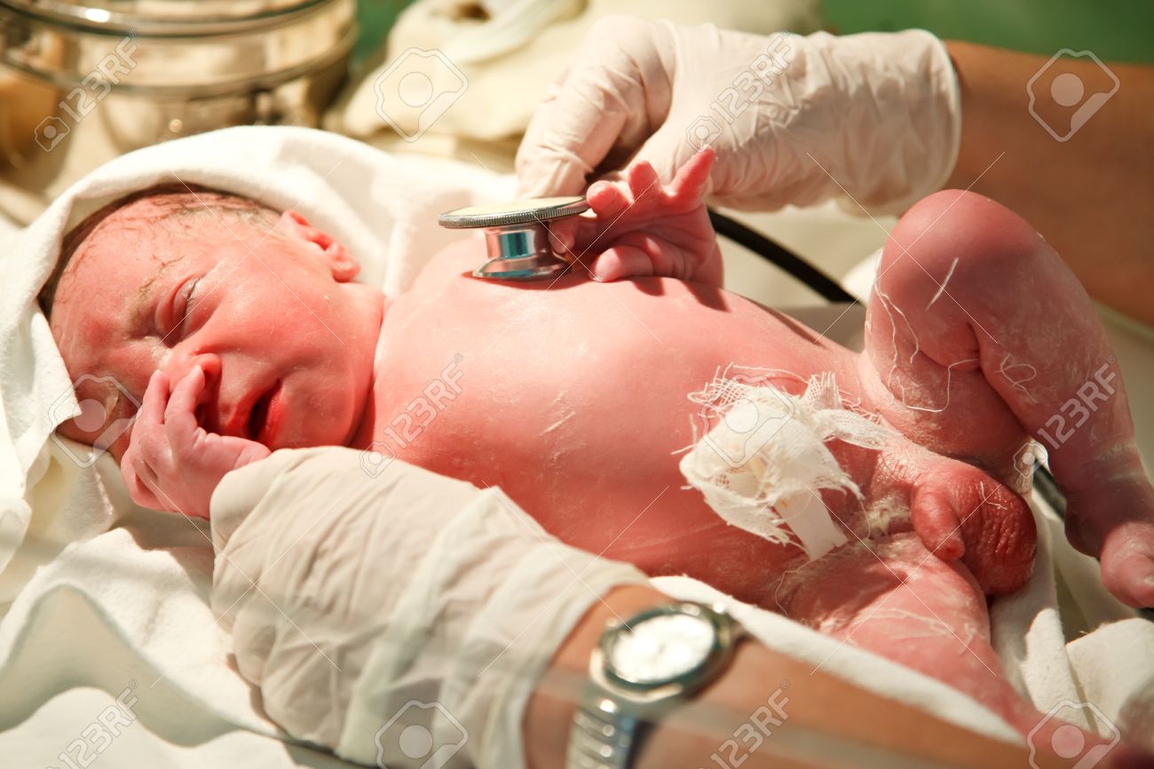 New born baby boy is being examined with a stethoscope after birth in the hospital stock