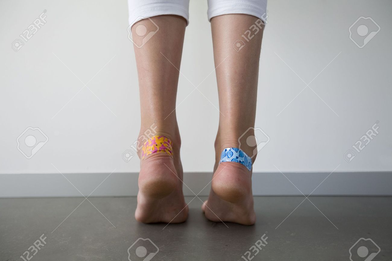 カラフルな接着剤で女の子は彼女のかかとに水ぶくれに絆創膏します の写真素材 画像素材 Image