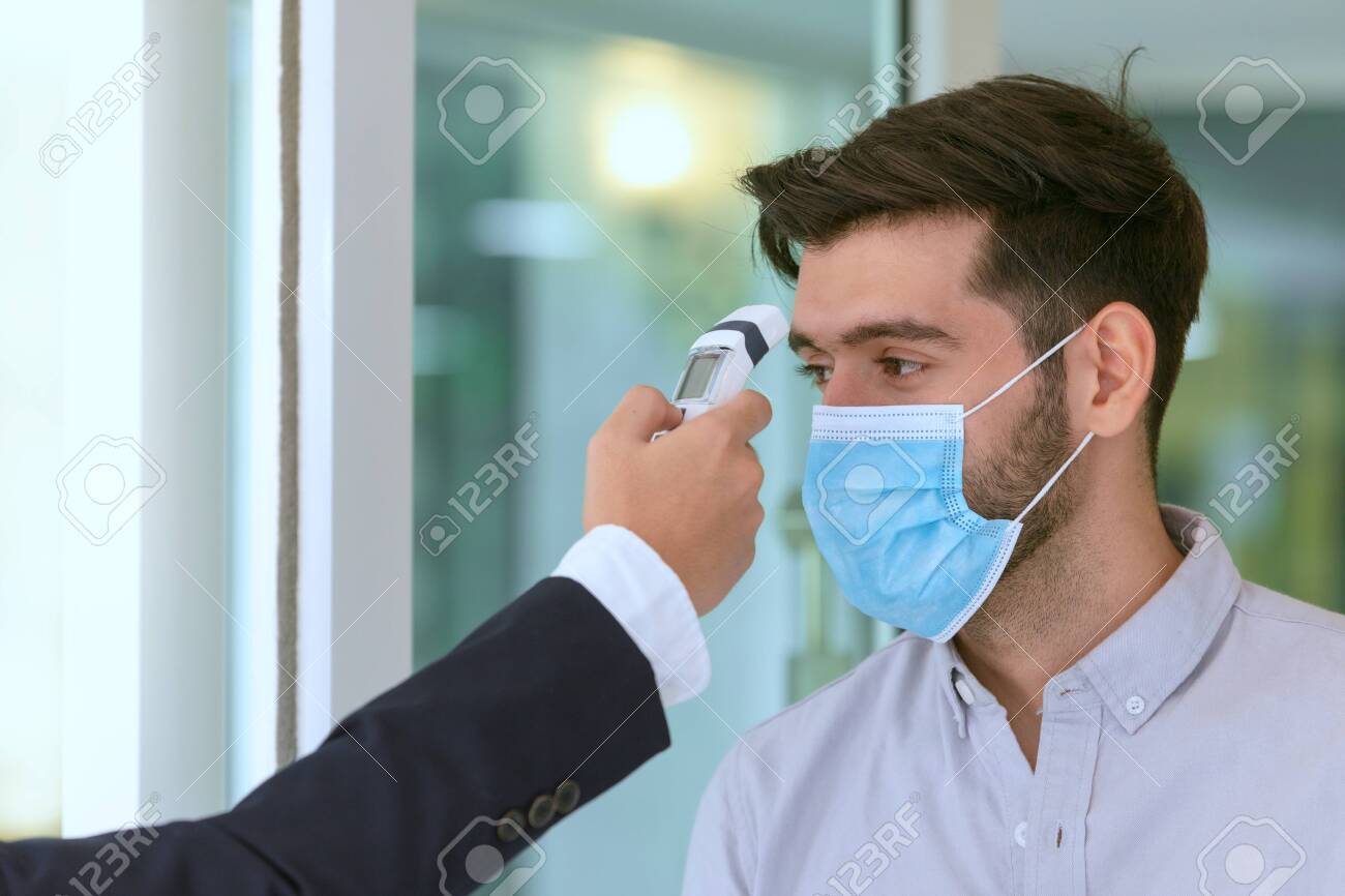 Body temperature check,Receptionist and guest wearing face mask at front desk while having conversation at hotel.Covid 19 and coronavirus infection protection and protective policy concept . - 155621795 Body temperature check,Receptionist and guest wearing face mask at front desk while having conversation at hotel.Covid 19 and coronavirus infection protection and protective policy concept . - 155621795