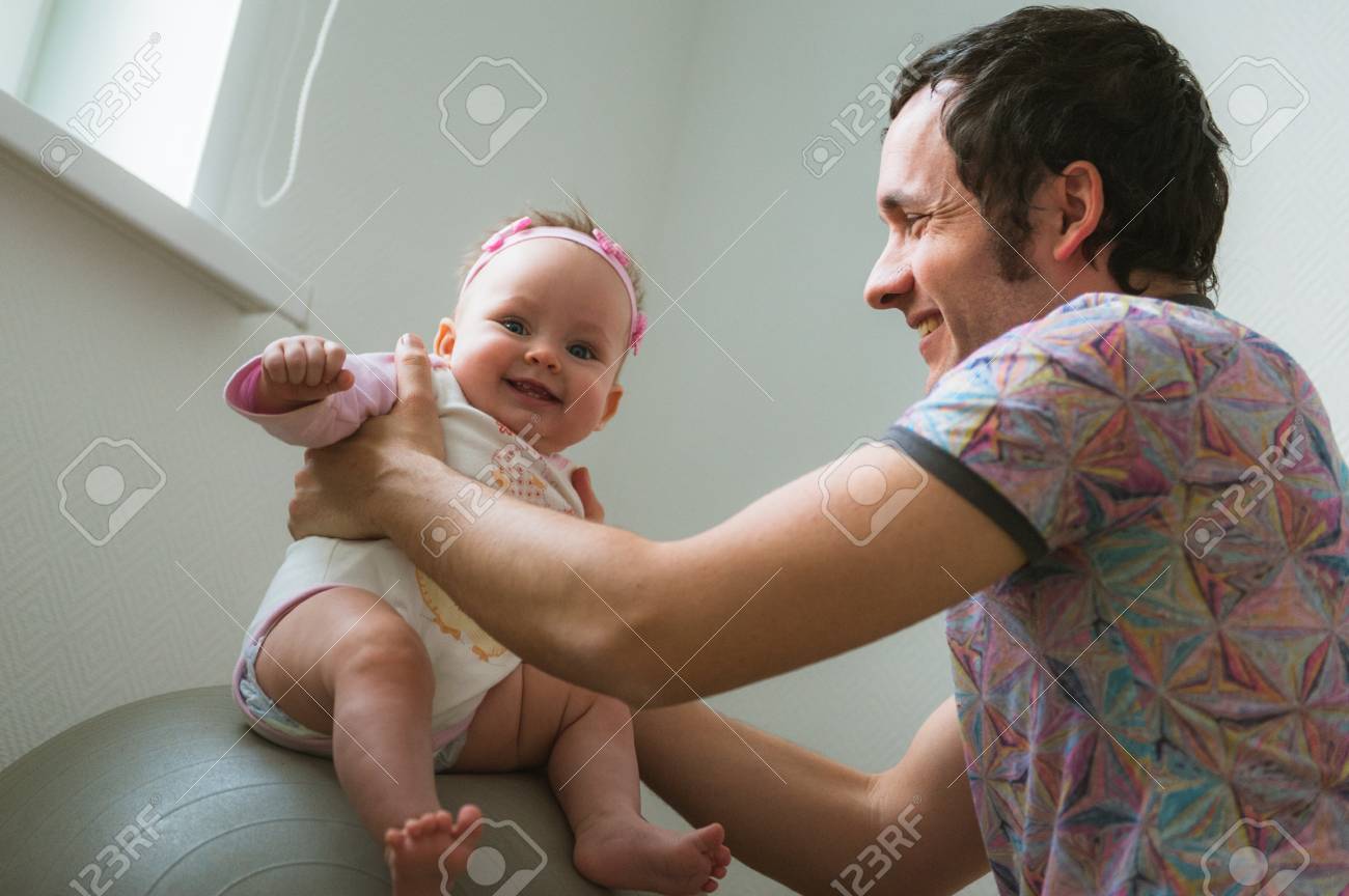 Image De Jeune Papa Avec Une Petite Fille Mignonne Dans Ses Bras Pere Et Bebe Fille A L Interieur Enfant Saute Sur La Balle Avec L Aide De Papa Banque D Images Et Photos Libres
