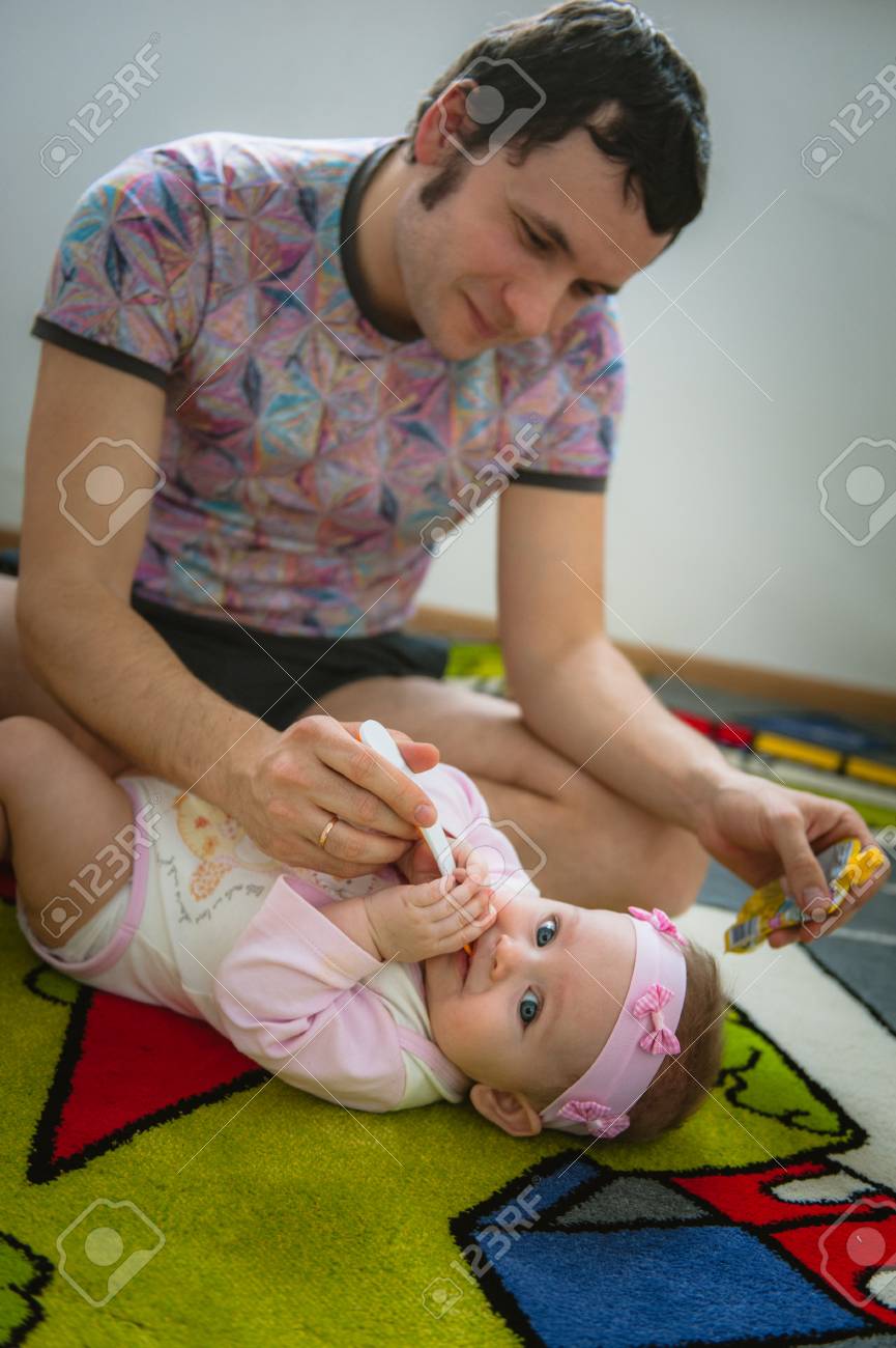 Papa Feeds Child With Spoon Image Of Young Dad With Cute Little Daughter On Floor At Home Father And Baby Girl Indoor Stock Photo Picture And Royalty Free Image Image