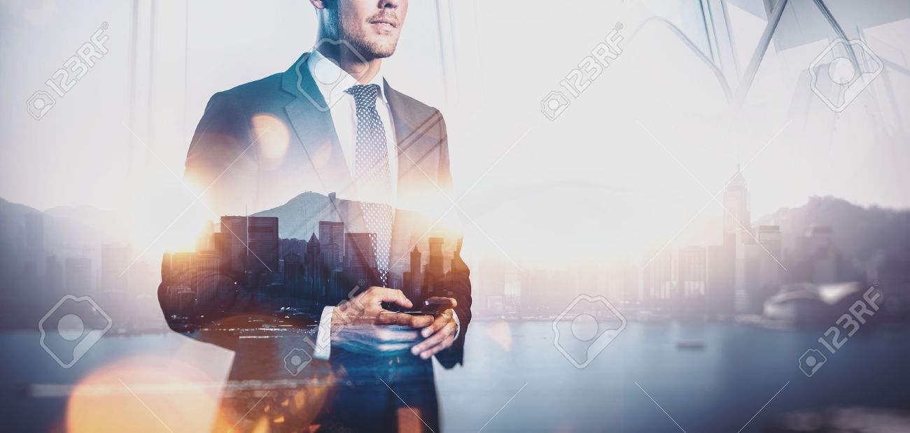 Photo of businessman holding smartphone. Double exposure photo of panoramic city view at sunrise - 52905773 Photo of businessman holding smartphone. Double exposure photo of panoramic city view at sunrise - 52905773