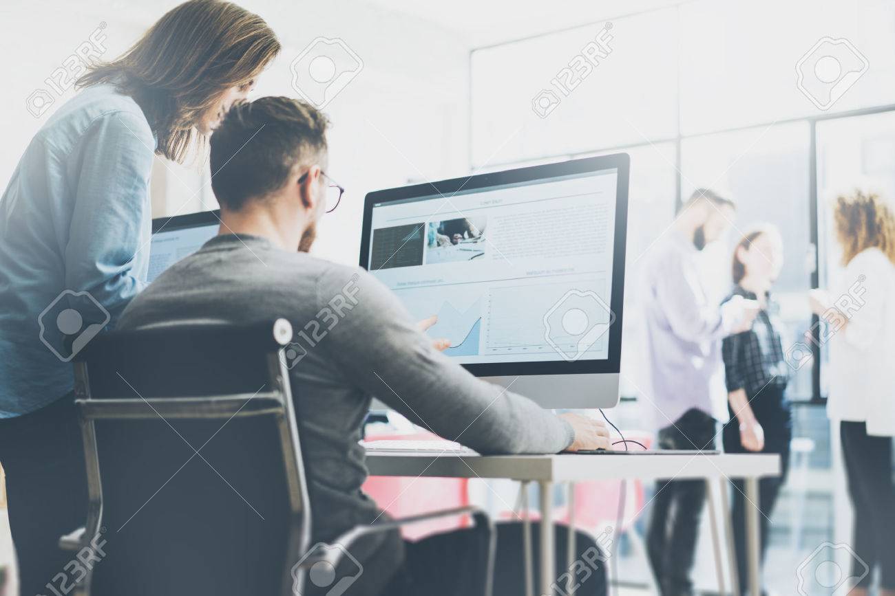 Coworking process, designers team working modern office.Photo young creative manager showing new startup idea monitor. Desktop computers on wood table. Blurred background, film effect. - 55448959 Coworking process, designers team working modern office.Photo young creative manager showing new startup idea monitor. Desktop computers on wood table. Blurred background, film effect. - 55448959