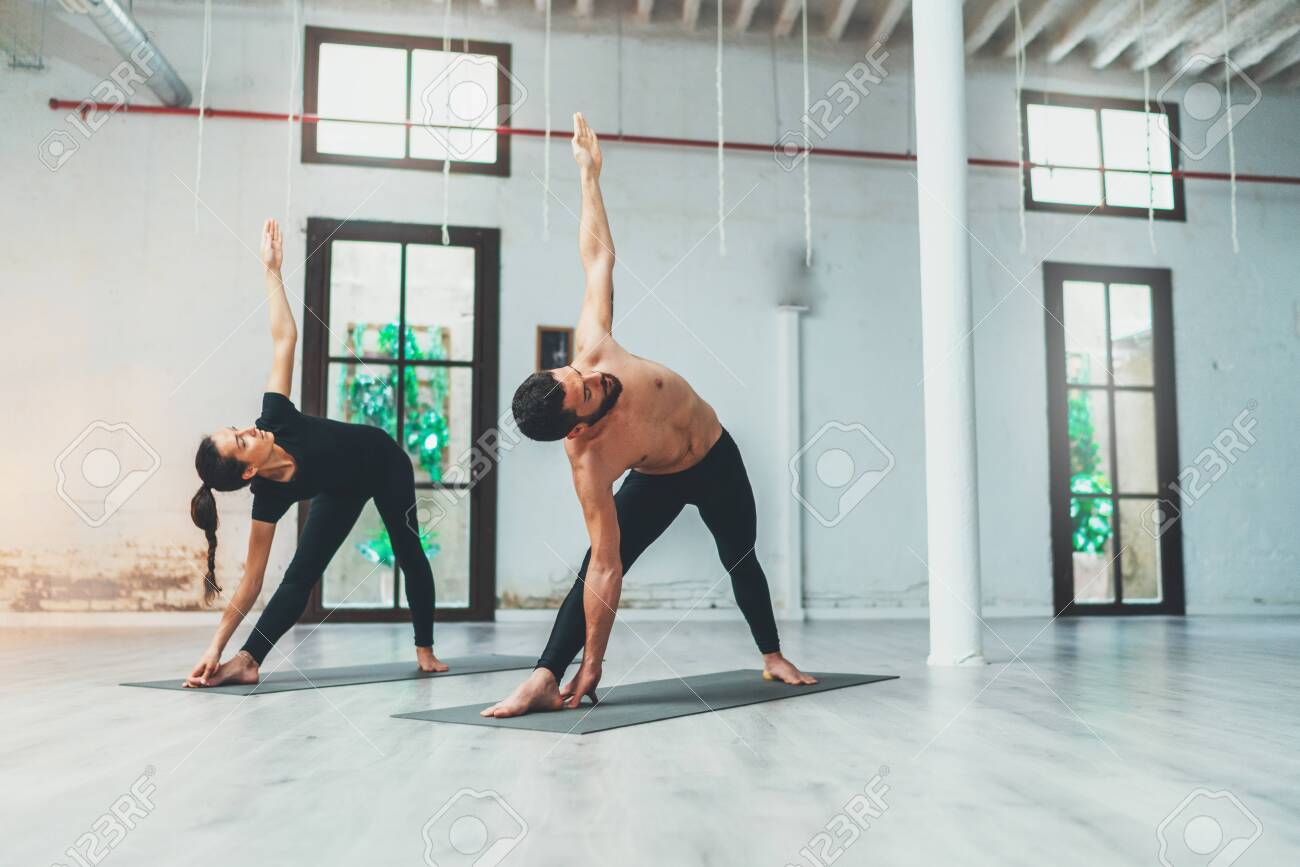 Couple Of Young Sporty People Practicing Yoga Lesson With Partner. Two People Doing Yoga Exercises. Stock Photo, Picture And Royalty Free Image. Image 127286988.