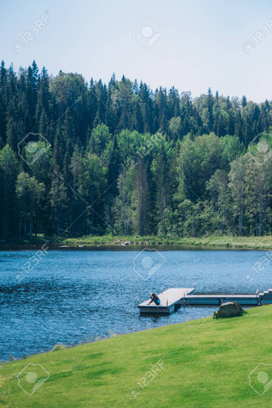 The girl sits on an empty pier on the scenic lake - 144990289 The girl sits on an empty pier on the scenic lake - 144990289