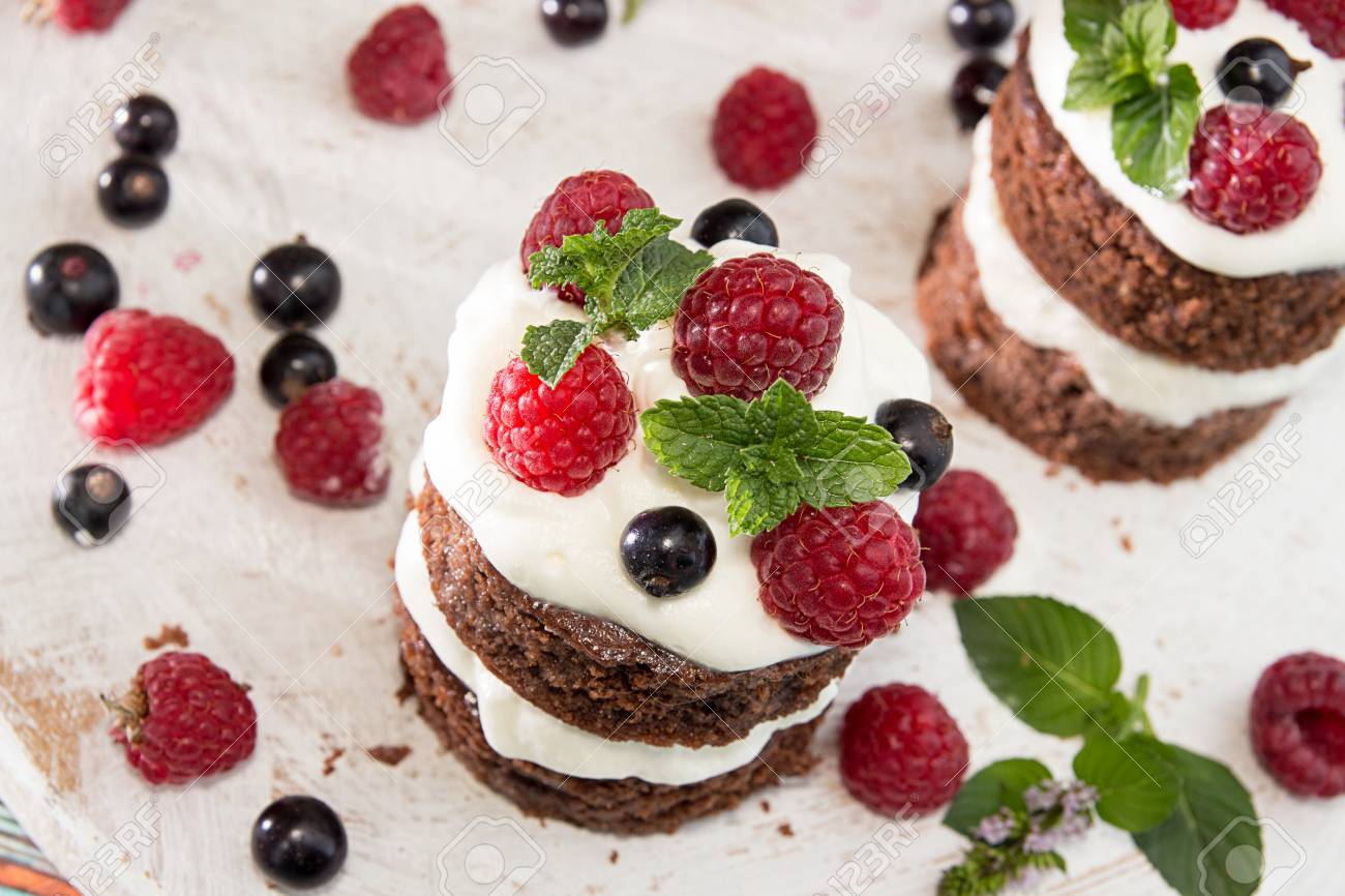 Gateau Au Chocolat Decore De Framboise De Cassis De Creme Chantilly Et De Menthe Sur Planche De Bois Blanc Vue De Dessus Banque D Images Et Photos Libres De Droits Image