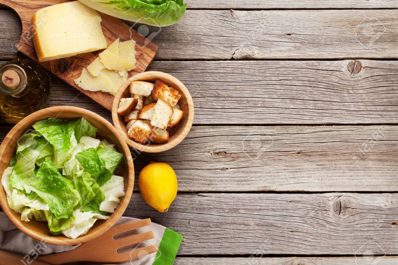 Fresh healthy caesar salad cooking on wooden table. Top view with copy space - 54581798 Fresh healthy caesar salad cooking on wooden table. Top view with copy space - 54581798