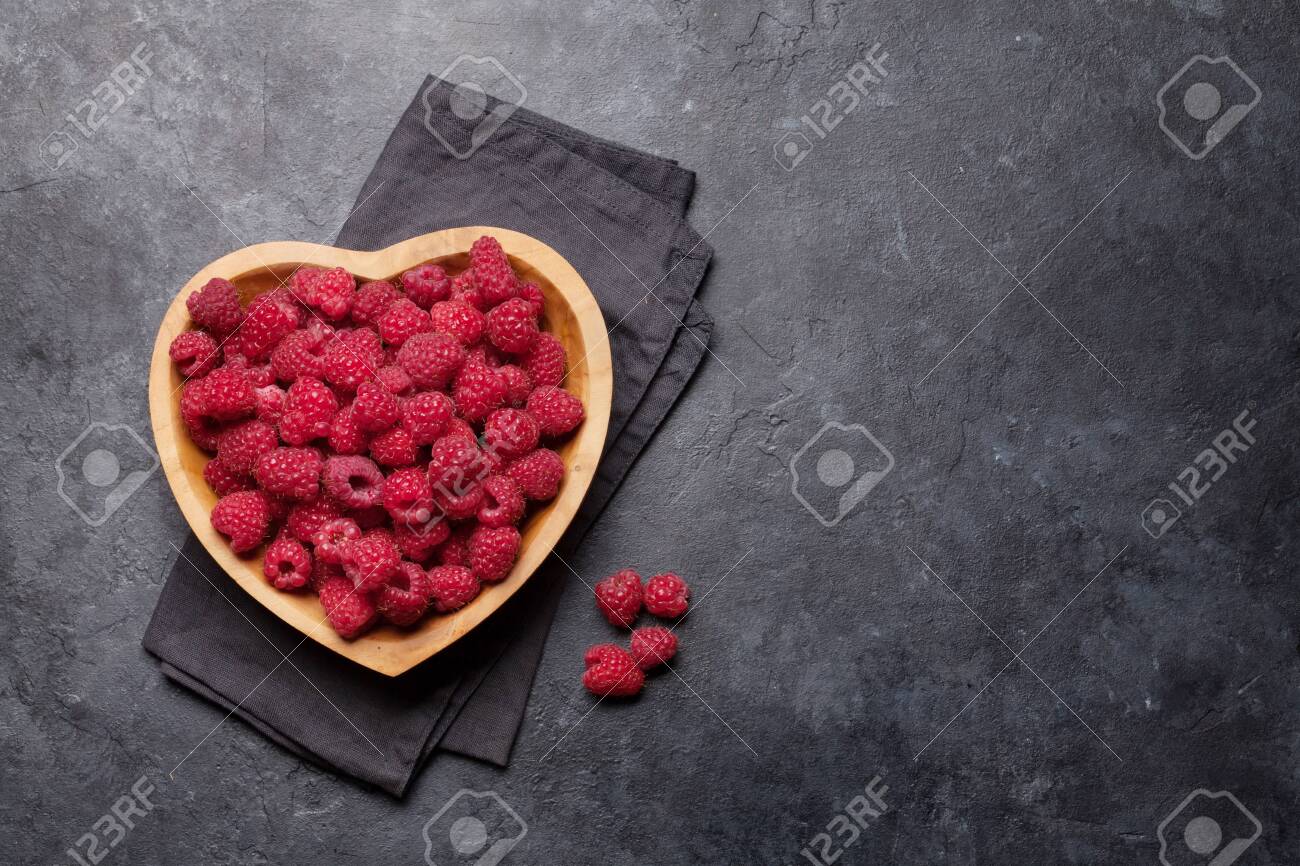Fresh ripe garden raspberry in heart shaped bowl on stone table. Top view with copy space - 133190875 Fresh ripe garden raspberry in heart shaped bowl on stone table. Top view with copy space - 133190875