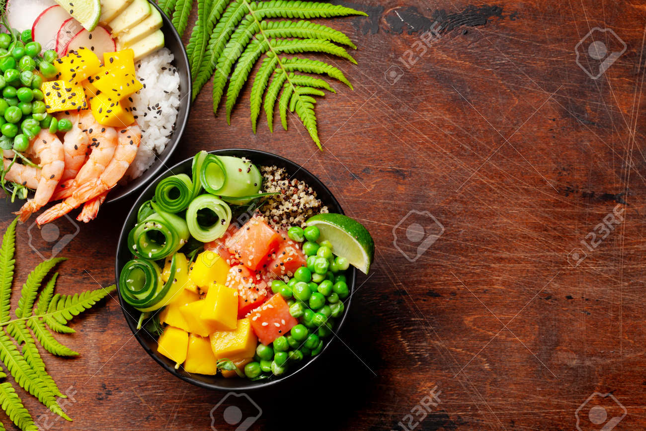 Poke bowls with shrimps, salmon, avocado and mango. Traditional hawaiian meal. Top view flat lay with copy space - 169549730 Poke bowls with shrimps, salmon, avocado and mango. Traditional hawaiian meal. Top view flat lay with copy space - 169549730