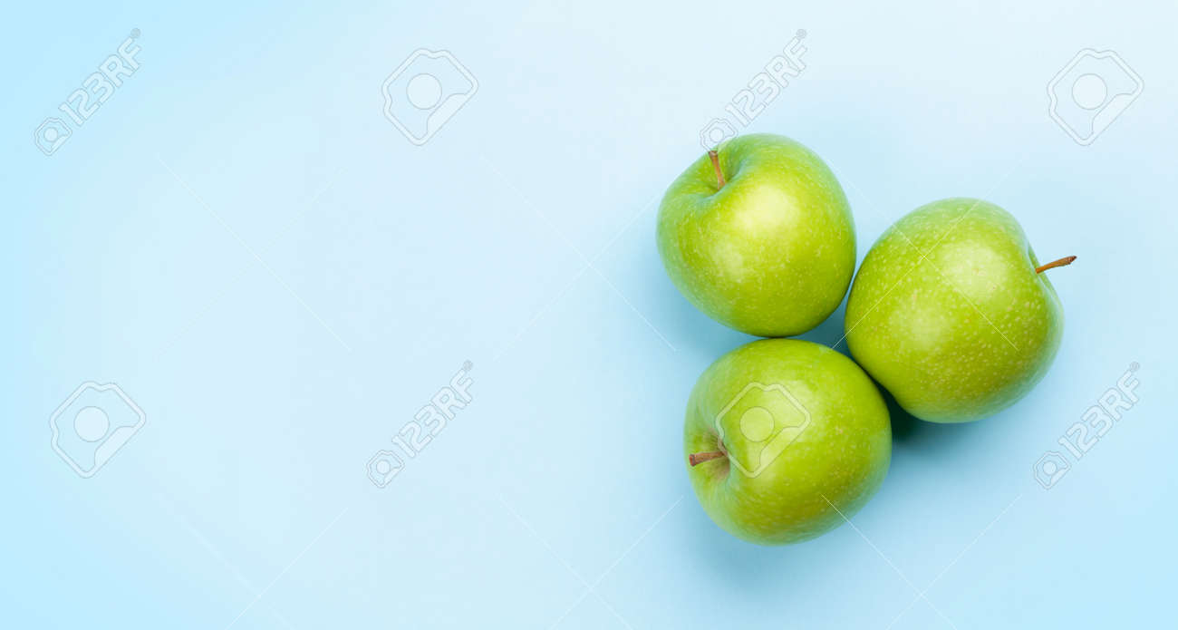 Fresh ripe green apple fruits on blue background. Top view flat lay with copy space - 169549908 Fresh ripe green apple fruits on blue background. Top view flat lay with copy space - 169549908