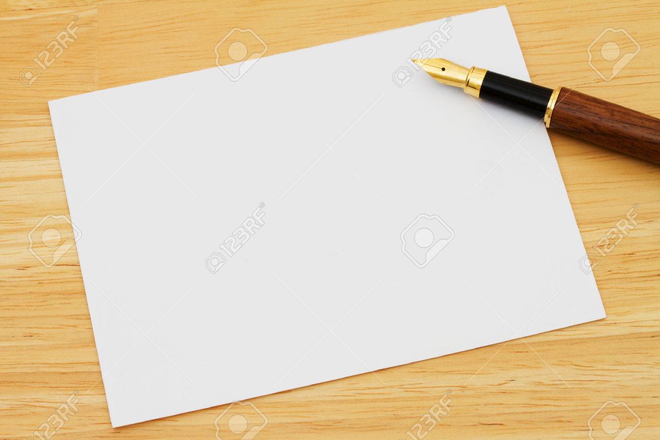 a blank card with a fountain pen on a wooden desk writing a stock