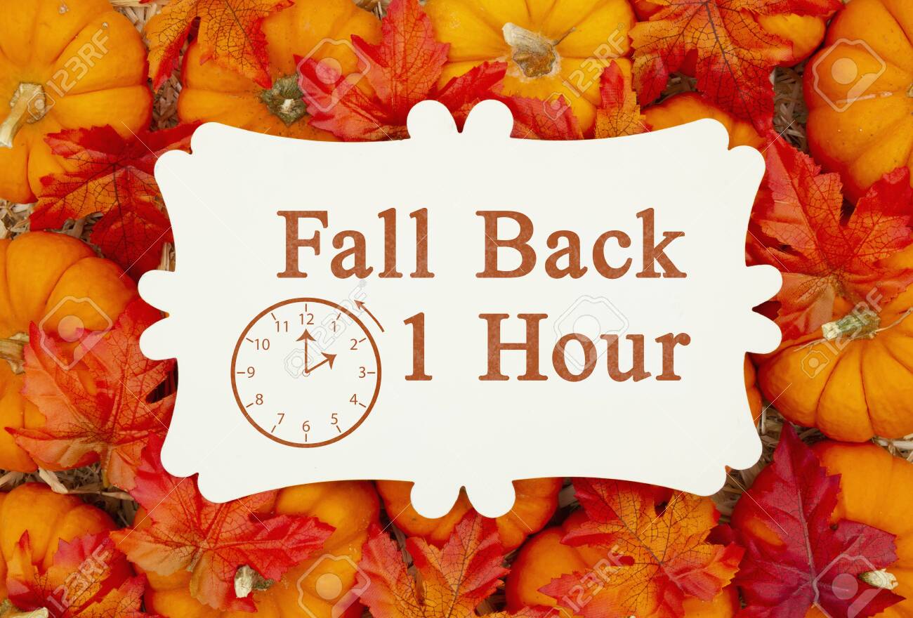 Fall Back 1 hour time change message on a metal sign on pumpkins and a straw hay - 132464124 Fall Back 1 hour time change message on a metal sign on pumpkins and a straw hay - 132464124