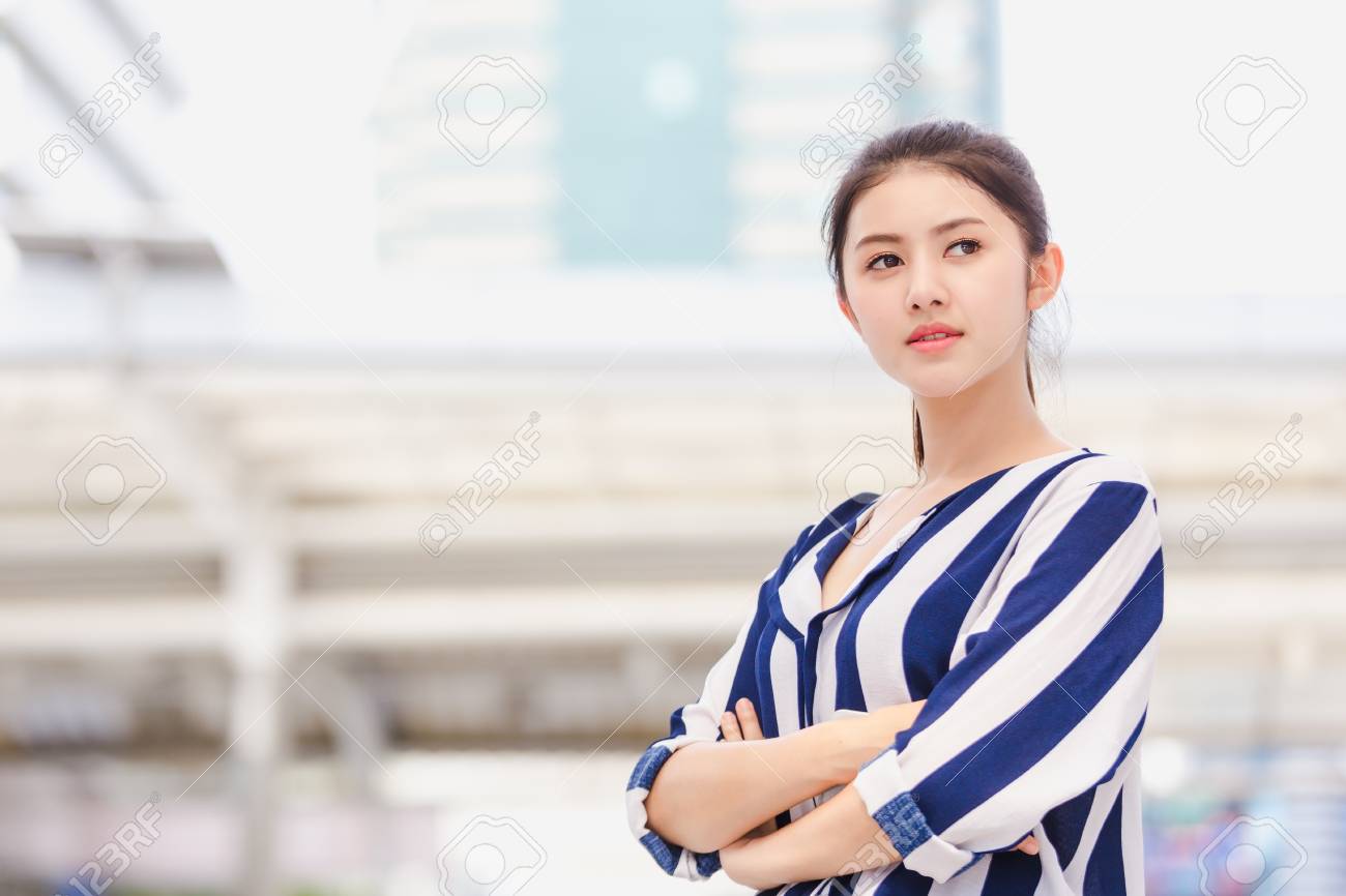Portrait of smiling pretty lifestyle young business woman standing pointing modern building background - 122269455 Portrait of smiling pretty lifestyle young business woman standing pointing modern building background - 122269455