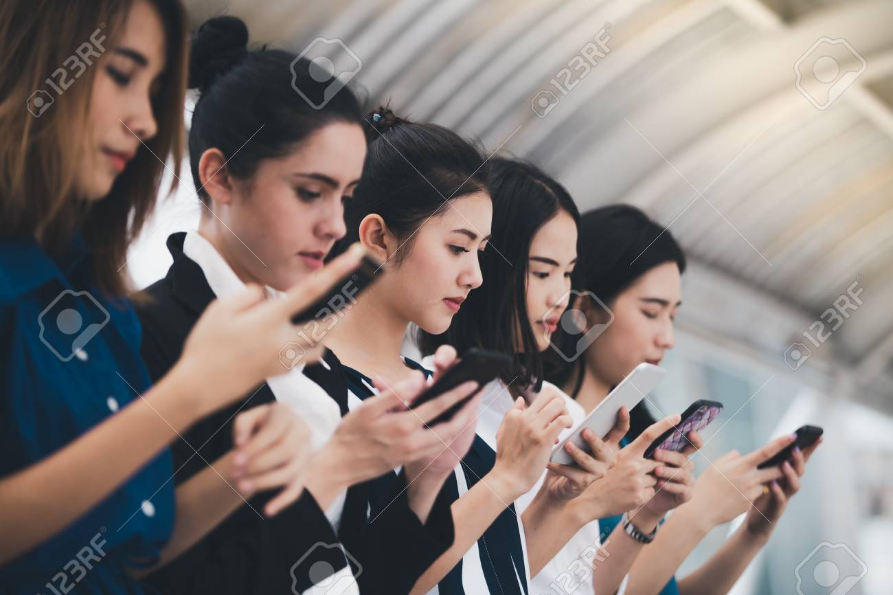 attractive asian businesswomen team playing smartphone outdoor city background - 122269909 attractive asian businesswomen team playing smartphone outdoor city background - 122269909