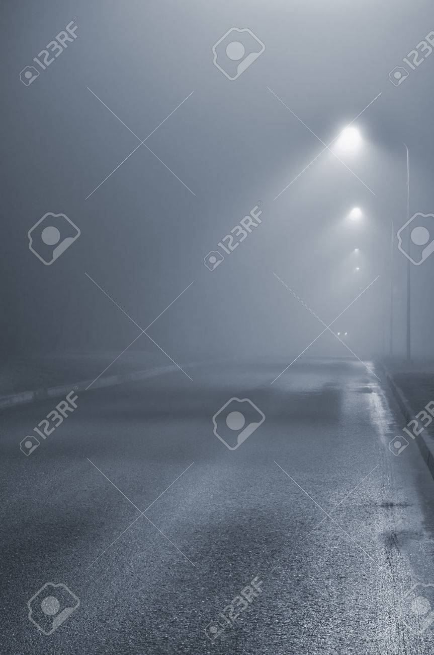 街路灯 霧霧の夜 ランプのポストのランタン 霧霧 濡れたアスファルト舗装 車のヘッドライトが近づいて 人けのない道の青いキー の写真素材 画像素材 Image