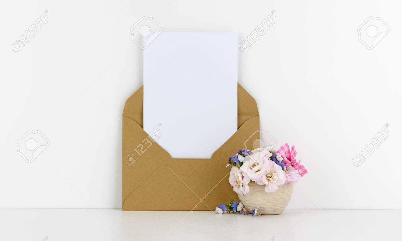 blank postcard mockup with craft paper envelope and white flowers