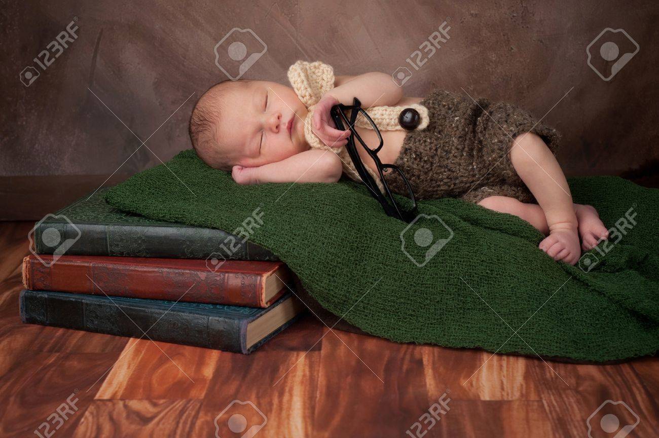 Cinq Jours Vieux Garcon Nouveau Ne Vetu D Un Short En Crochet Un Noeud Papillon Et Bretelles Il Tient Des Lunettes De Lecture Pour Adultes Et Dormant Sur Une Pile De Livres Anciens Banque
