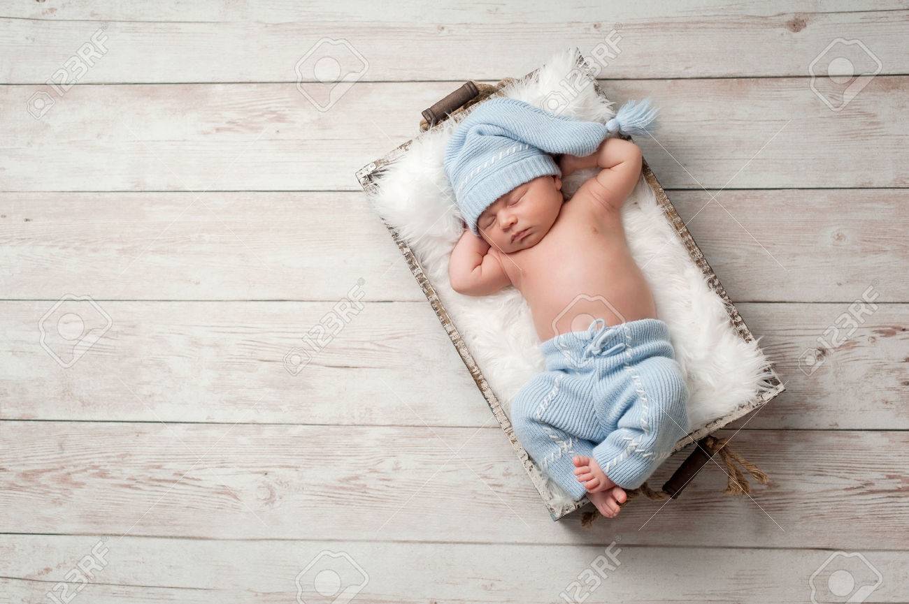 Newborn Baby Sleeping In A Wooden Crate On A Whitewashed Wooden