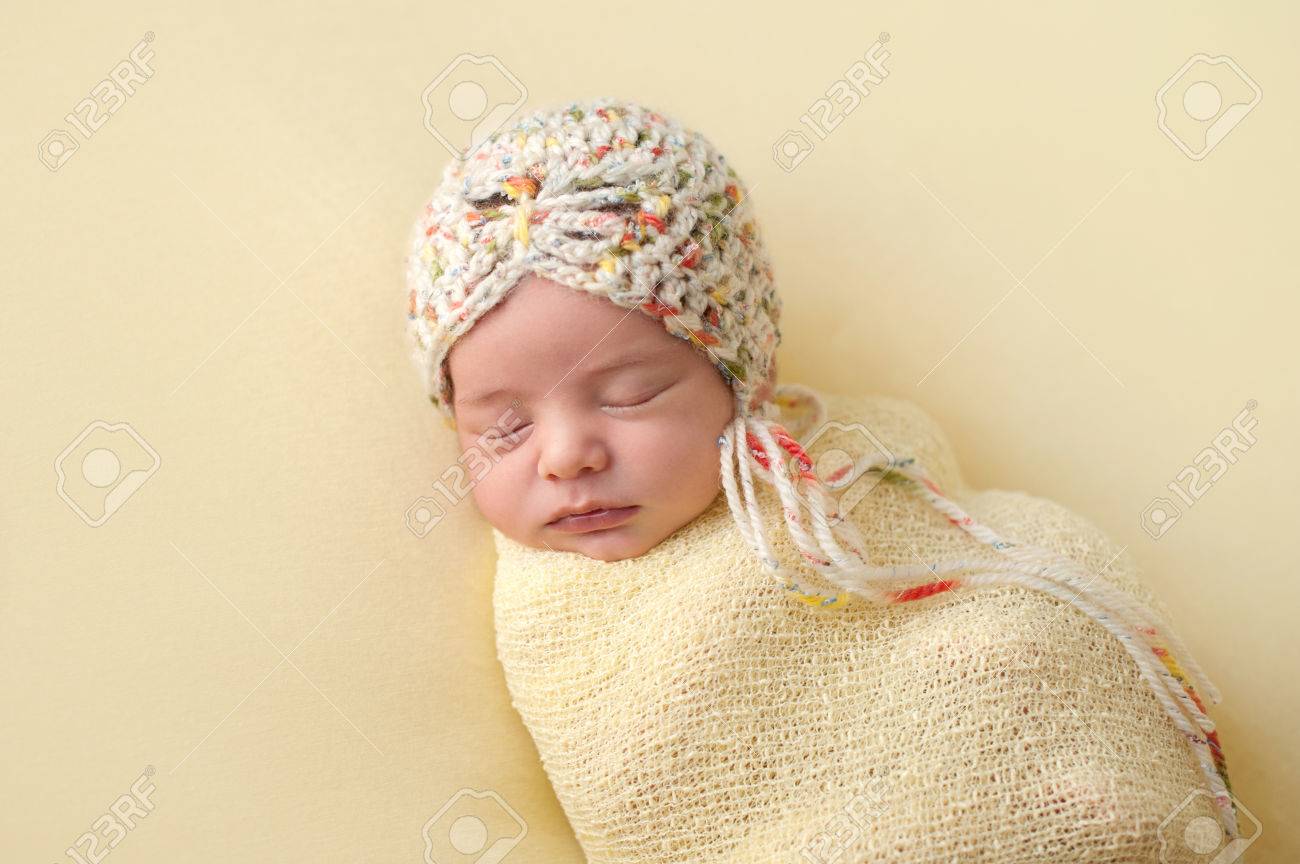 かぎ針編みのボンネットを身に着けている美しい 睡眠 2 週齢 新生児の赤ちゃんの女の子の肖像画 彼女は薄物 黄色の布で Swaddled です の写真素材 画像素材 Image
