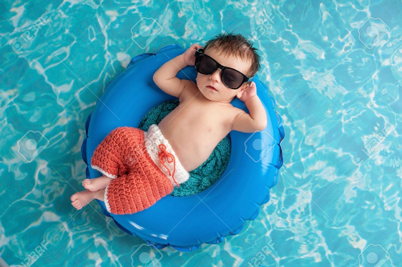 Three week old newborn baby boy sleeping on a tiny inflatable swim ring. He is wearing crocheted board shorts and black sunglasses. - 48645122 Three week old newborn baby boy sleeping on a tiny inflatable swim ring. He is wearing crocheted board shorts and black sunglasses. - 48645122