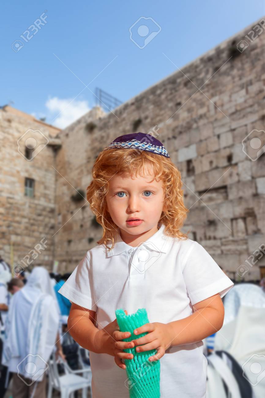 92823091-autumn-jewish-holiday-sukkot-lovely-blonde-boy-with-blue-eyes-in-a-skullcap-the-western-wall-of-the-.jpg