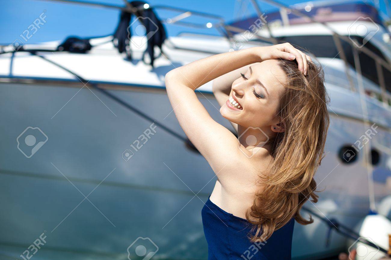 Young beautiful brunette woman relaxing on the dock near the boat on a sunny day in spring - 16349381 Young beautiful brunette woman relaxing on the dock near the boat on a sunny day in spring - 16349381
