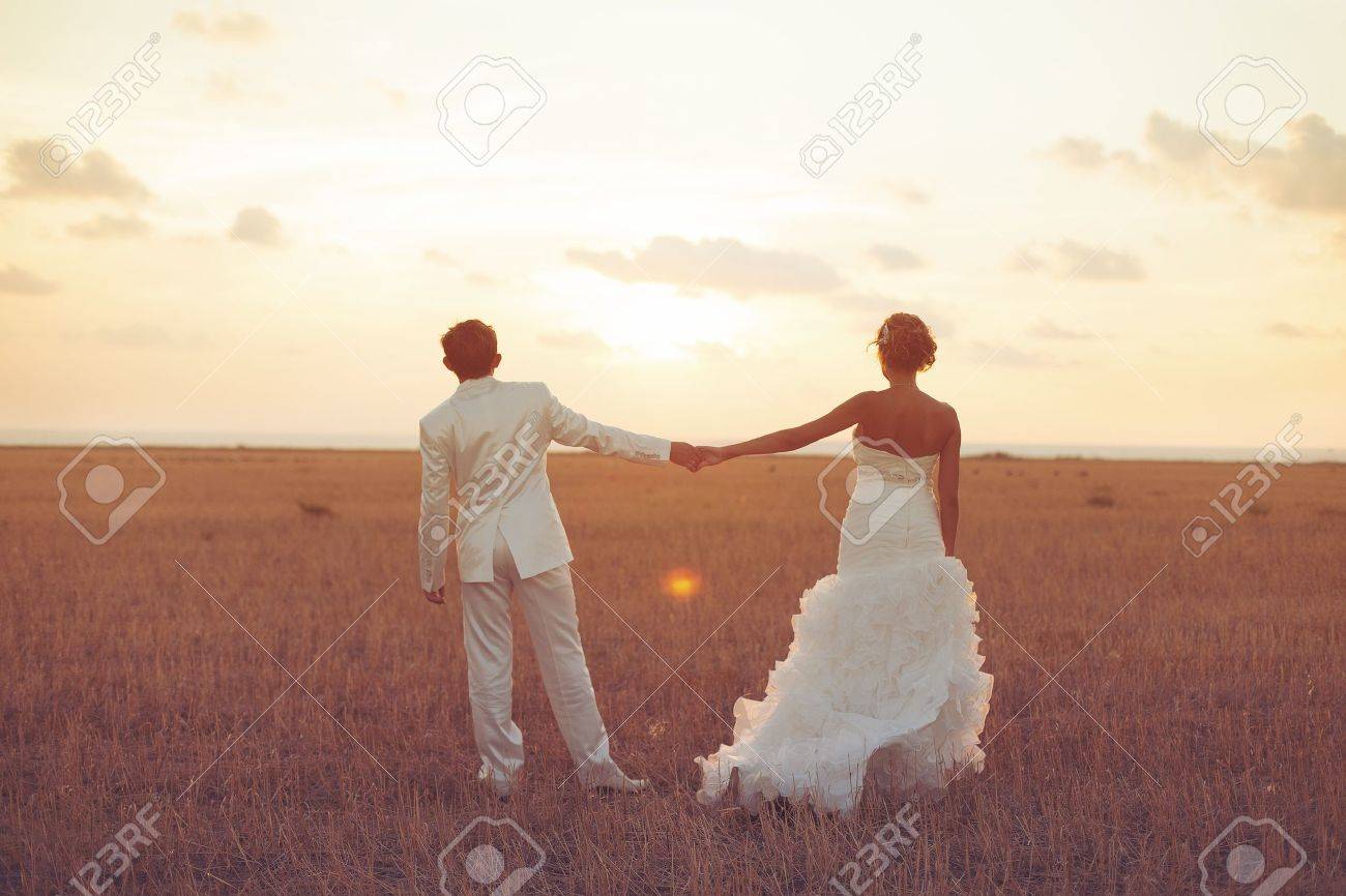 Young couple in love bride and groom posing in a field with yellow grass on sunset background in their wedding day in the summer Series - 16536974 Young couple in love bride and groom posing in a field with yellow grass on sunset background in their wedding day in the summer Series - 16536974