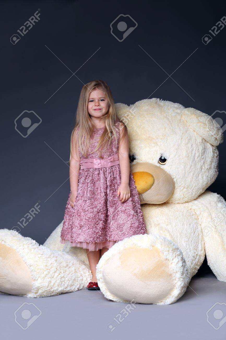 巨大なテディベア ぬいぐるみ ぬいぐるみ 大きなぬいぐるみ 子供とギフト 薄紫色のドレス ブロンドの女の子 スタジオでは 赤ちゃんが近くの女の子 の写真素材 画像素材 Image