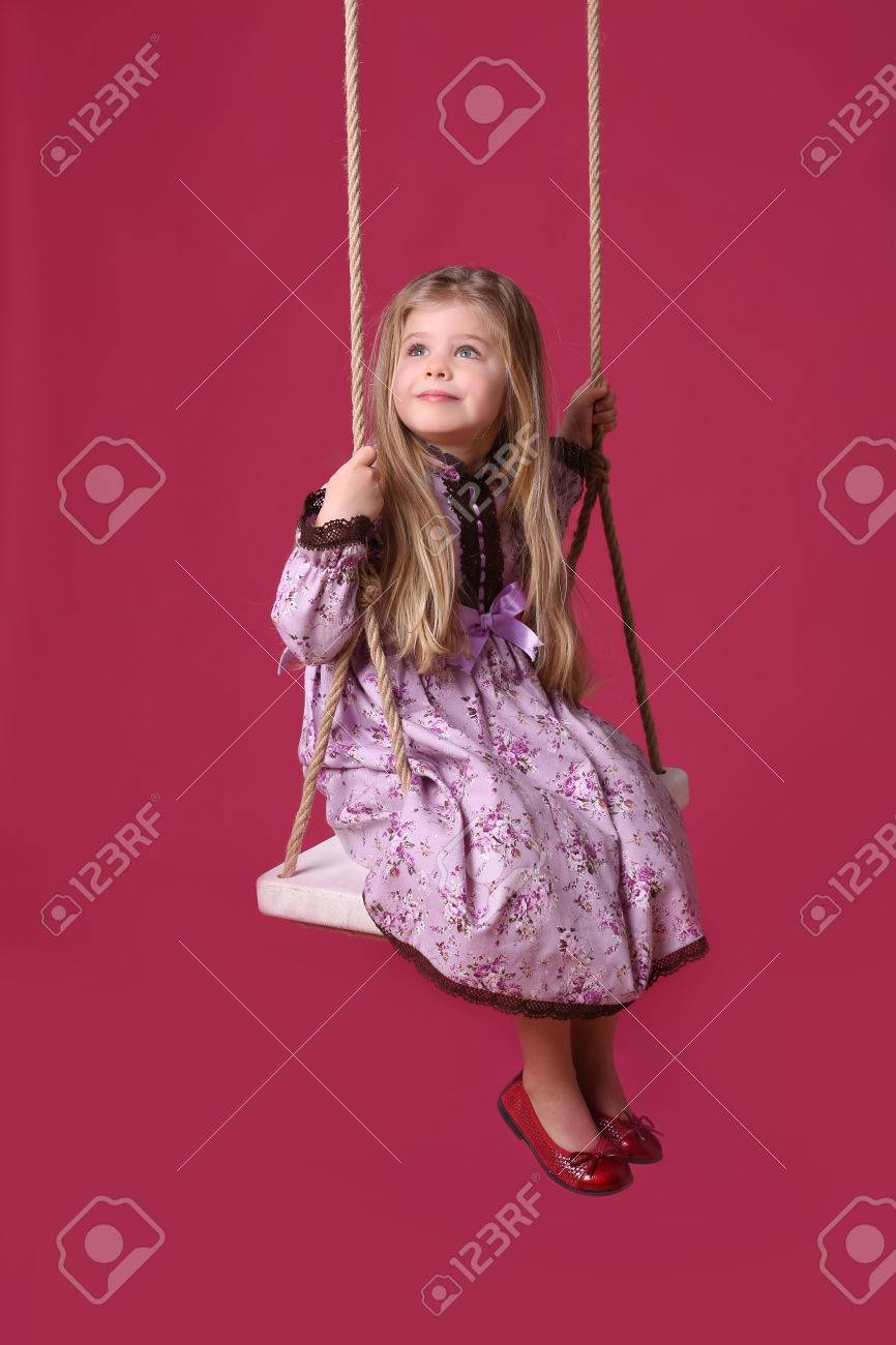 Enfant Chevauchant Sur Une Balancoire Equipement De Jeu Les Jouets A Bascule Aire De Jeux Pour Les Enfants Robe Lilas Fille Blonde Bebe En Studio Fond Rouge Banque D Images Et Photos Libres