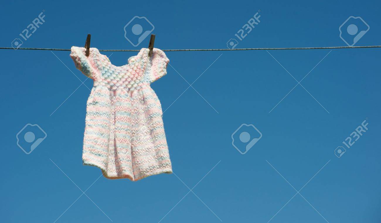 A Grandmothers Hand Knitted Baby Dress Hangs Drying On A Clothesline