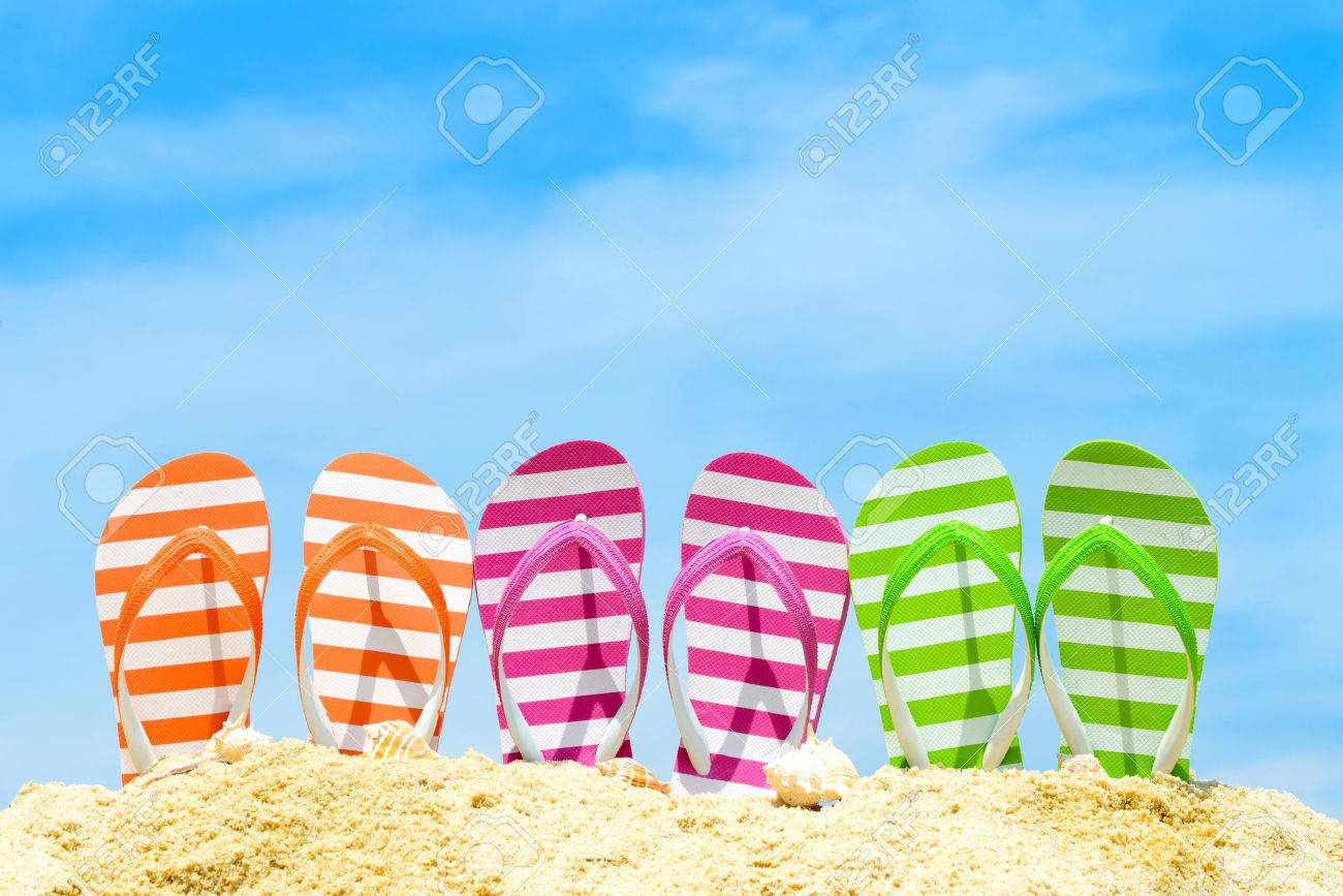 Row of multicolor flip flops on beach against blue sky - 39643499 Row of multicolor flip flops on beach against blue sky - 39643499