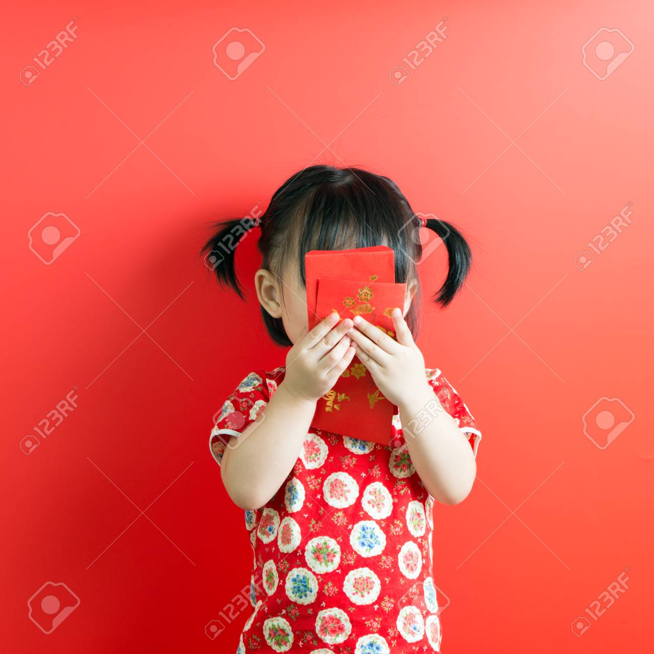 Little Asian girl holding red envelope on red background - 93215259 Little Asian girl holding red envelope on red background - 93215259