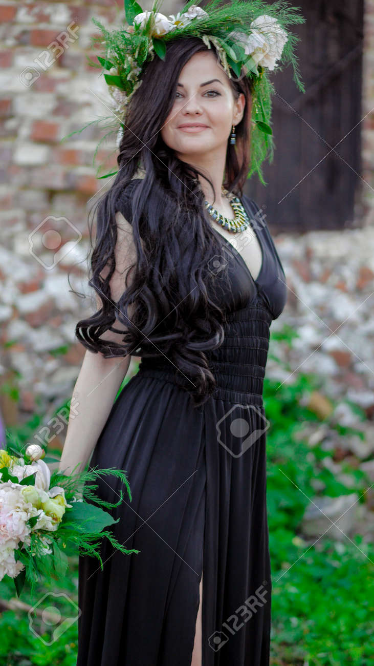 Woman in the spring. A wreath of meadow grass and flowers is worn on the brunettes head. White peonies adorn the head of a young lady. A girl in a long black sleeveless dress. - 151458813 Woman in the spring. A wreath of meadow grass and flowers is worn on the brunettes head. White peonies adorn the head of a young lady. A girl in a long black sleeveless dress. - 151458813