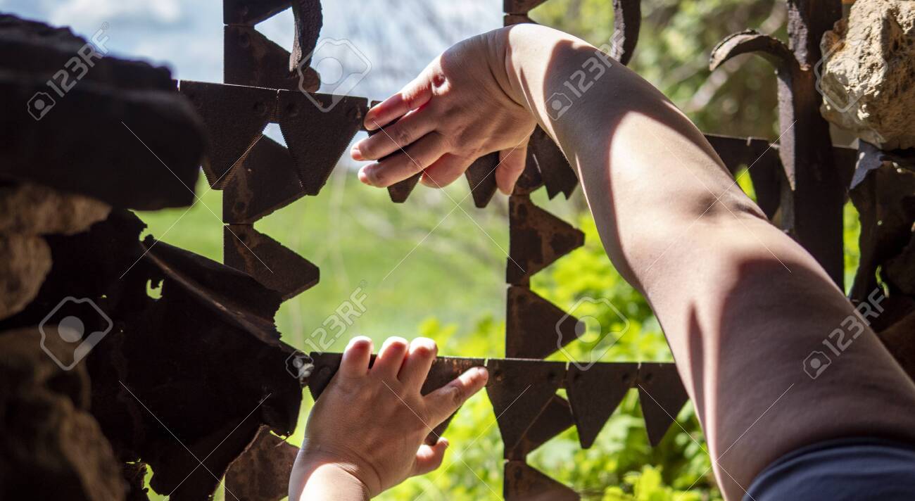 Hands reach for the metal bars in the window. Outside the window, the landscape was beautiful. - 149481566 Hands reach for the metal bars in the window. Outside the window, the landscape was beautiful. - 149481566